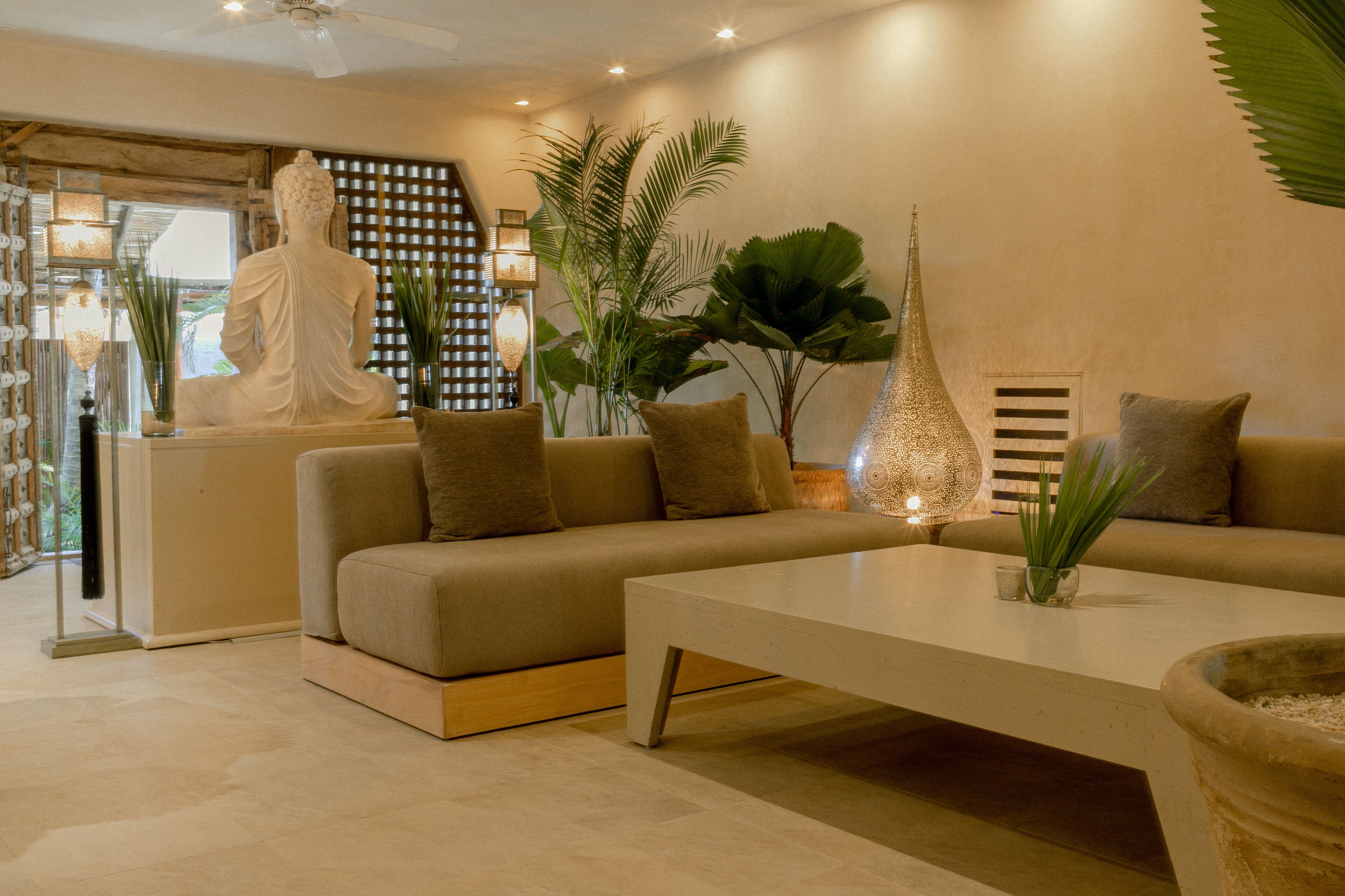 A modern living room with a sofa, a coffee table, and a Buddha statue.