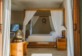 A bedroom with a four-poster bed, wooden nightstands, a television, and a decorative object on the nightstand.