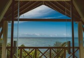A view from a covered area with a glass wall, overlooking the ocean.