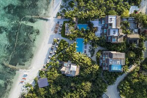 Vista aérea de un resort con varias construcciones, una piscina y una playa.