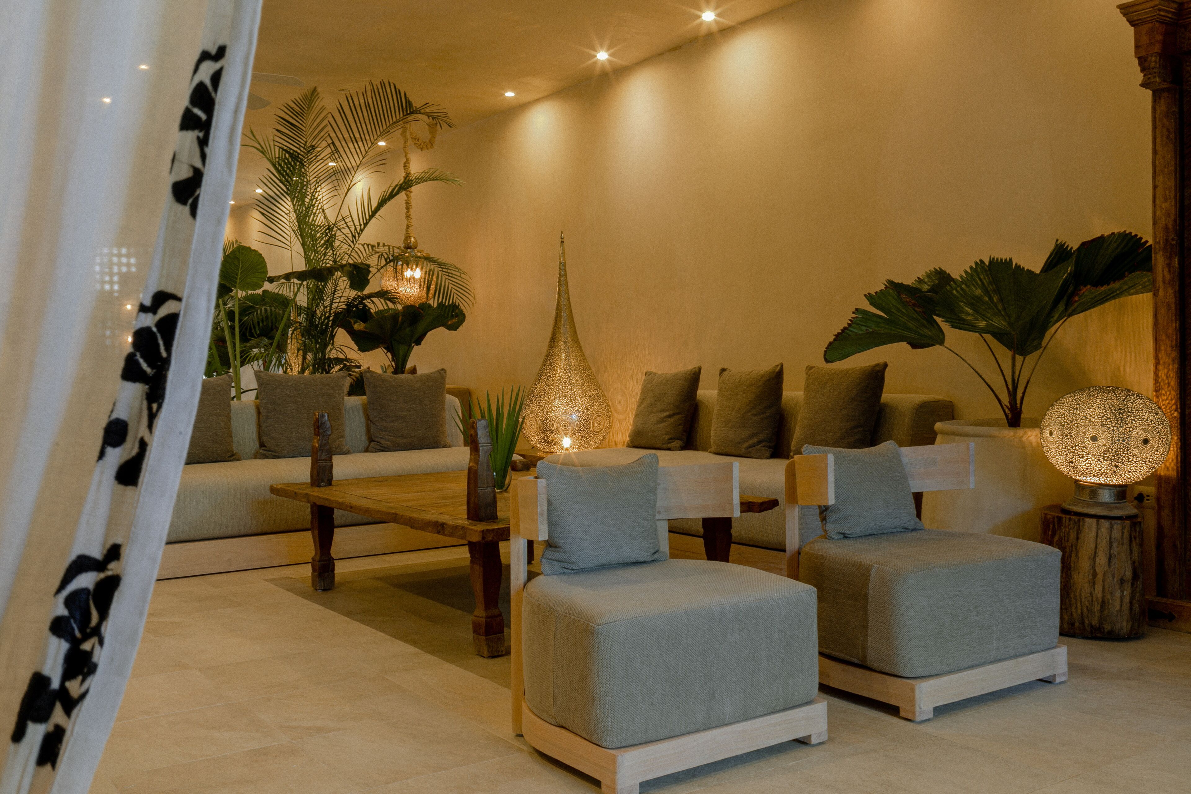 A modern living room with a sofa, ottoman, coffee table, and decorative lamps.