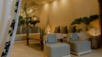 A modern living room with a sofa, ottoman, coffee table, and decorative lamps.