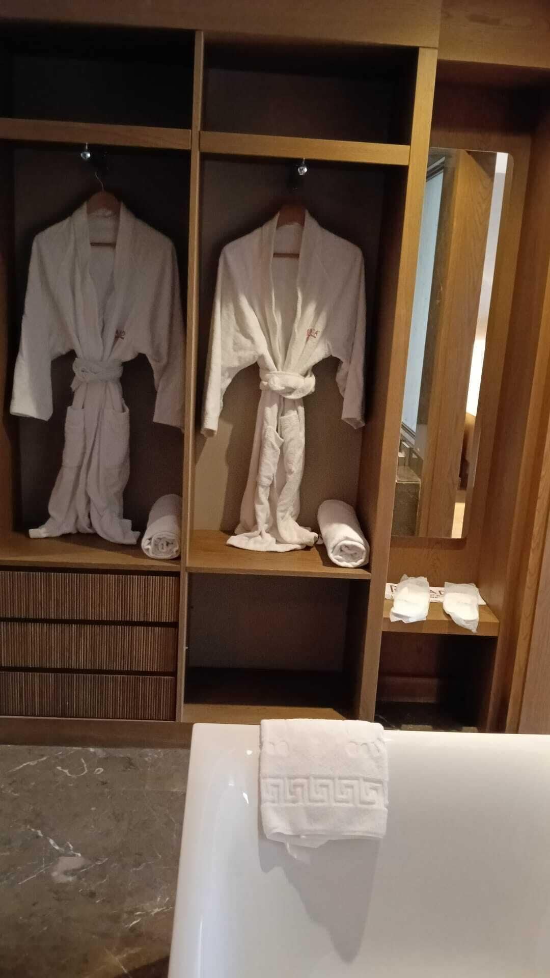 Un perchero de madera con dos albornoces blancos y una toalla.