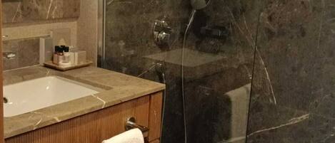 A bathroom with a marble sink, a mirror, a towel rack, and a shower area.