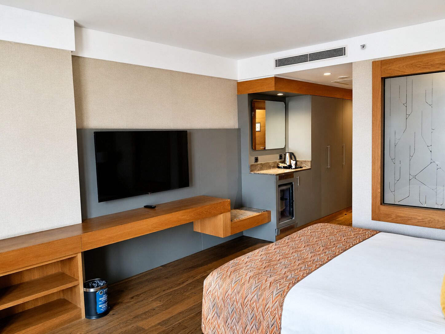 Habitació d'hotel amb un llit, televisió, petita cuineta i bany.