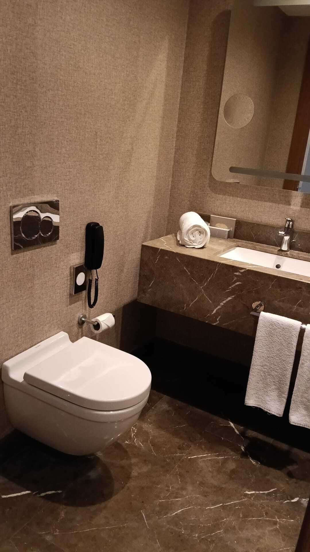 Un baño con inodoro, lavabo, espejo y teléfono.