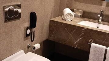 Un baño con inodoro, lavabo, espejo y teléfono.