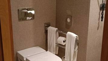 Un baño con inodoro, toallero e imagen enmarcada en la pared.