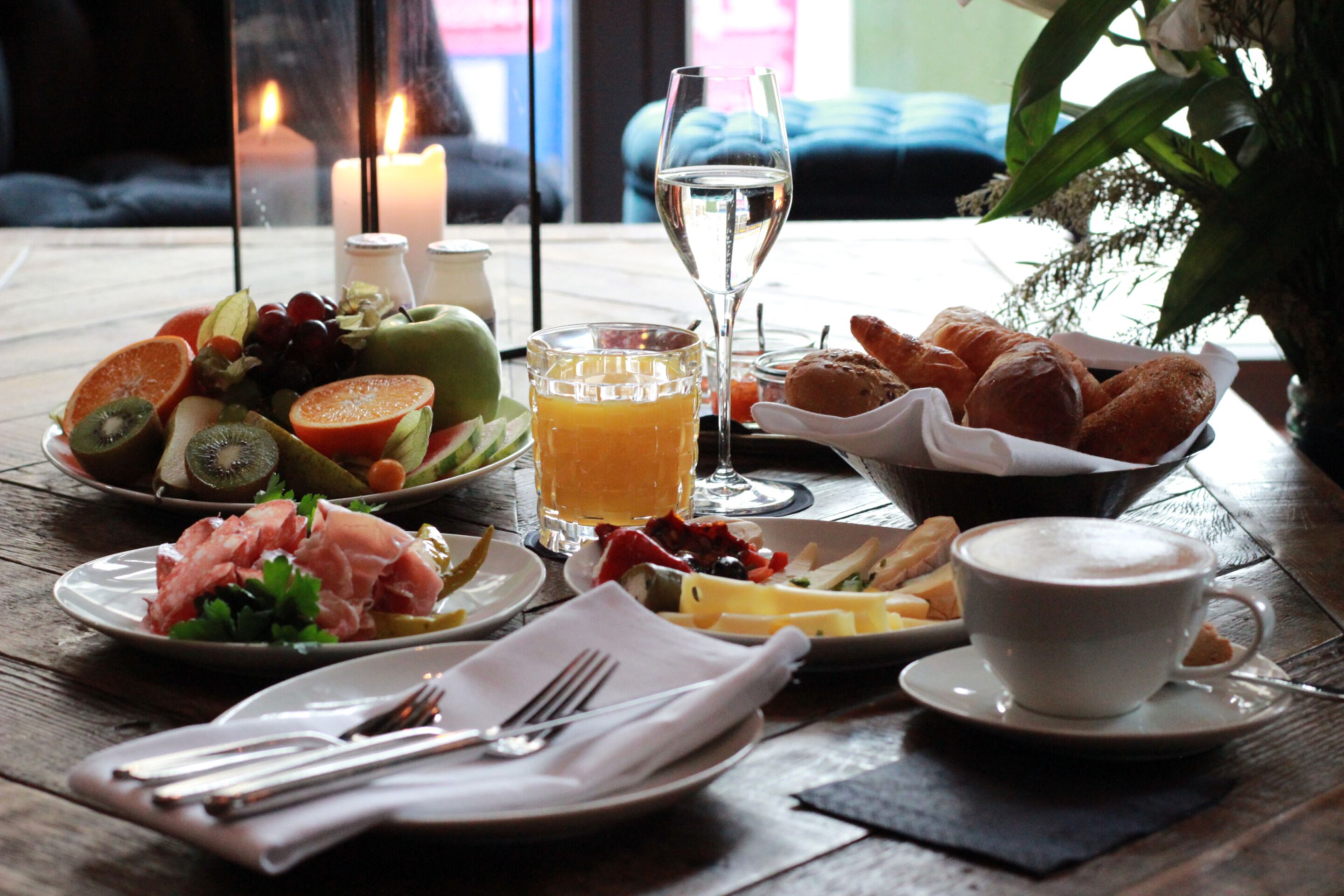 Un desayuno con diversas opciones de comida, un vaso de jugo y una taza de café sobre una mesa de madera.