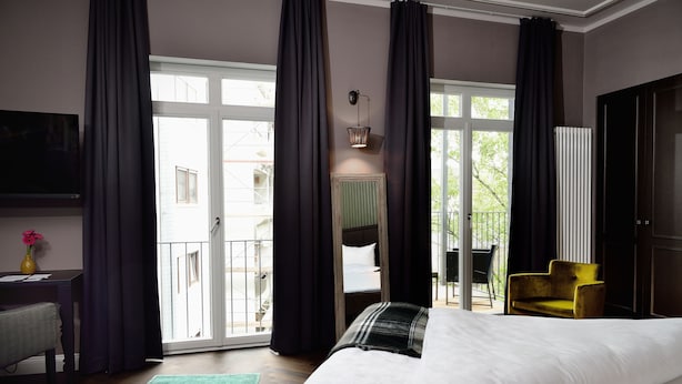 Un dormitorio con una cama grande, un escritorio, una silla, un sofá y vistas al exterior.