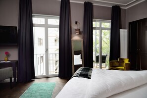 A bedroom with a large bed, a desk, a chair, a sofa, and a view of the outside. - Syte Boutique Hotel Mannheim (Mannheim)