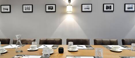 Una sala de conferències amb una taula llarga, cadires i quadres a la paret.