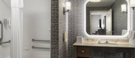 Une salle de bain moderne avec une douche, un meuble-lavabo avec un miroir et des murs carrelés.