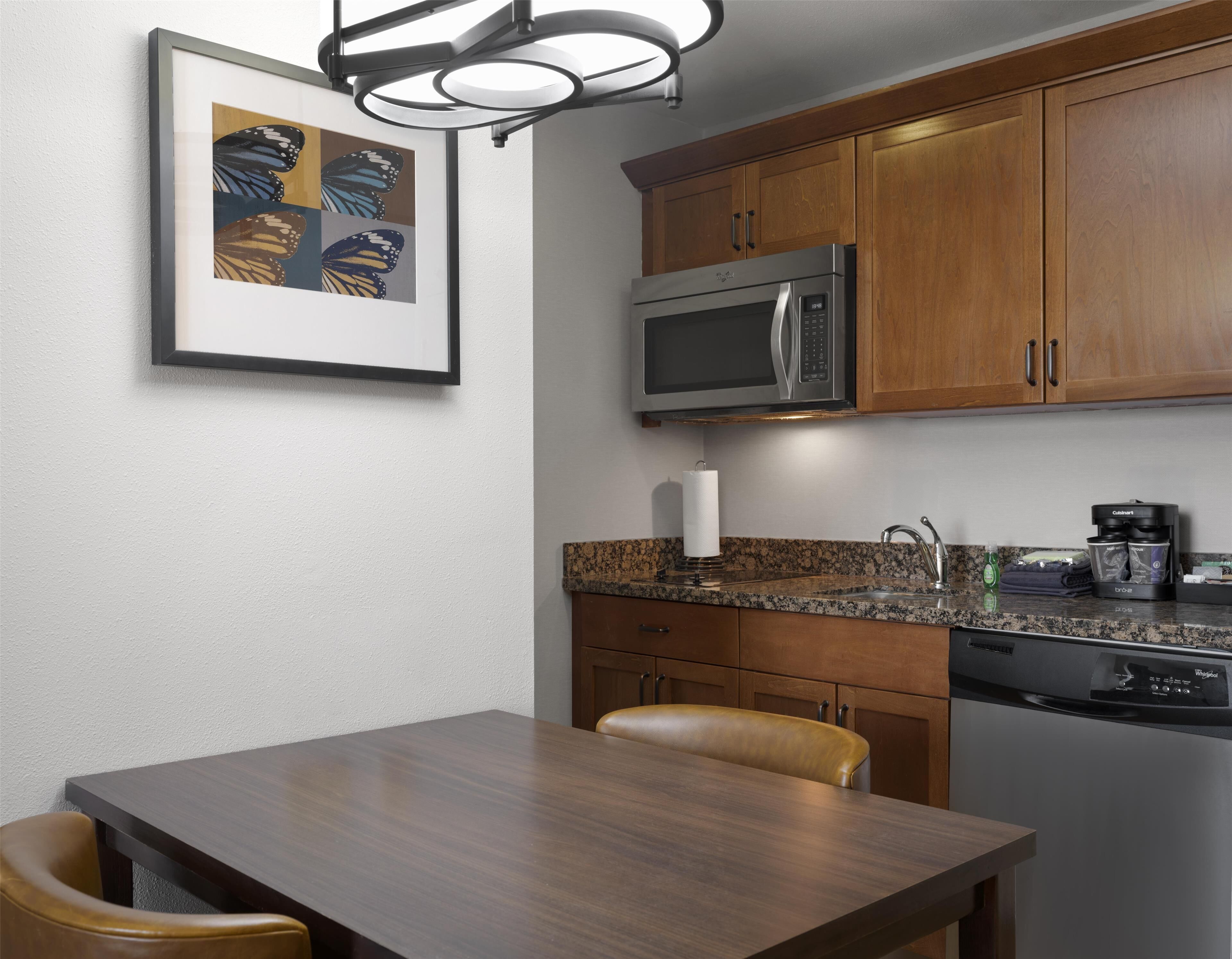 A modern kitchen with wooden cabinets, a stainless steel microwave, a coffee maker, and a dishwasher.