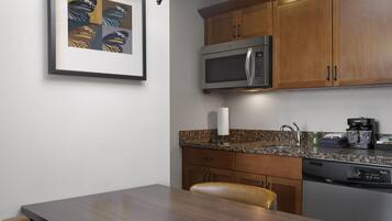 A modern kitchen with wooden cabinets, a stainless steel microwave, a coffee maker, and a dishwasher.