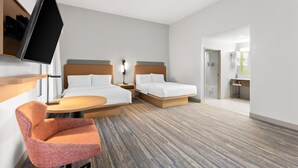 Een hotelkamer met twee bedden, een televisie, een stoel en een tafeltje.
