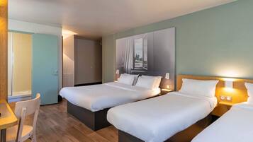A hotel room with two beds, a desk, and a chair.