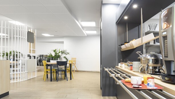 A modern kitchen with a breakfast bar, a coffee machine, and a fruit container. - B&B HOTEL Lyon Centre Monplaisir (Lyon)