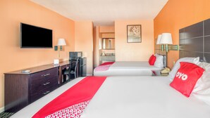 A hotel room with two beds, a desk, a TV, and a bathroom visible through an open door. - Sienna Inn Channelview, TX (Channelview)