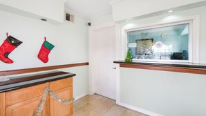 A hallway with a wooden cabinet, a white door, and two Christmas stockings on the wall. - Sienna Inn Channelview, TX (Channelview)