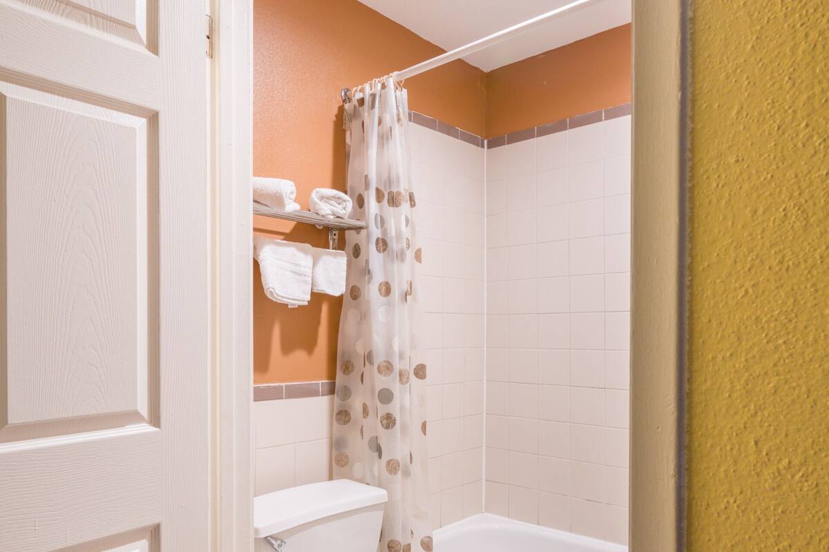 A bathroom with a toilet, bathtub, and shower curtain.