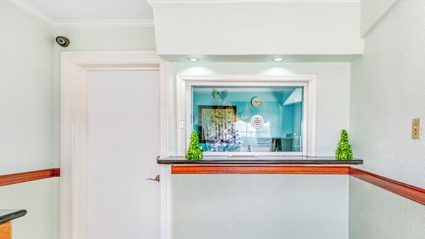 A reception area with a glass door, a wooden counter, and a small plant. - Sienna Inn Channelview, TX (Channelview)