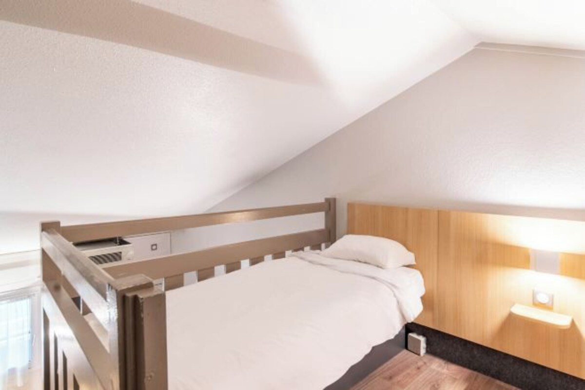 A bedroom with a bunk bed, a bedside table, and a wall-mounted light.
