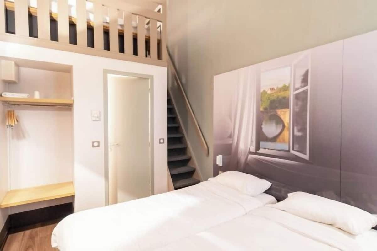 A bedroom with a bed, a wardrobe, a door, and a staircase.