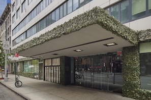 A modern building with a covered entrance, large windows, and a bike parked outside. - Truss Hotel Times Square  (New York)