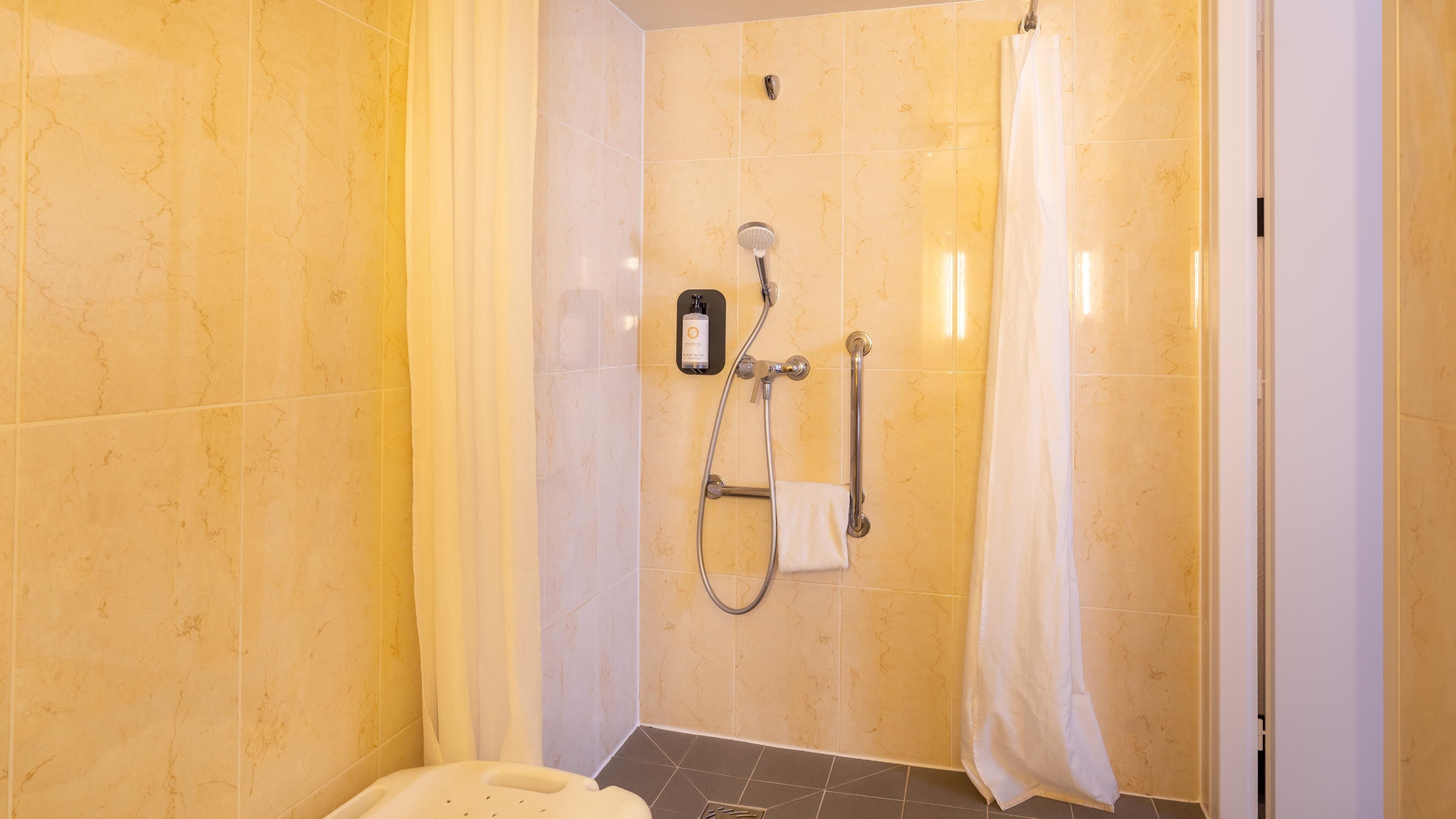 Un baño con ducha, toallero y una botella de champú.
