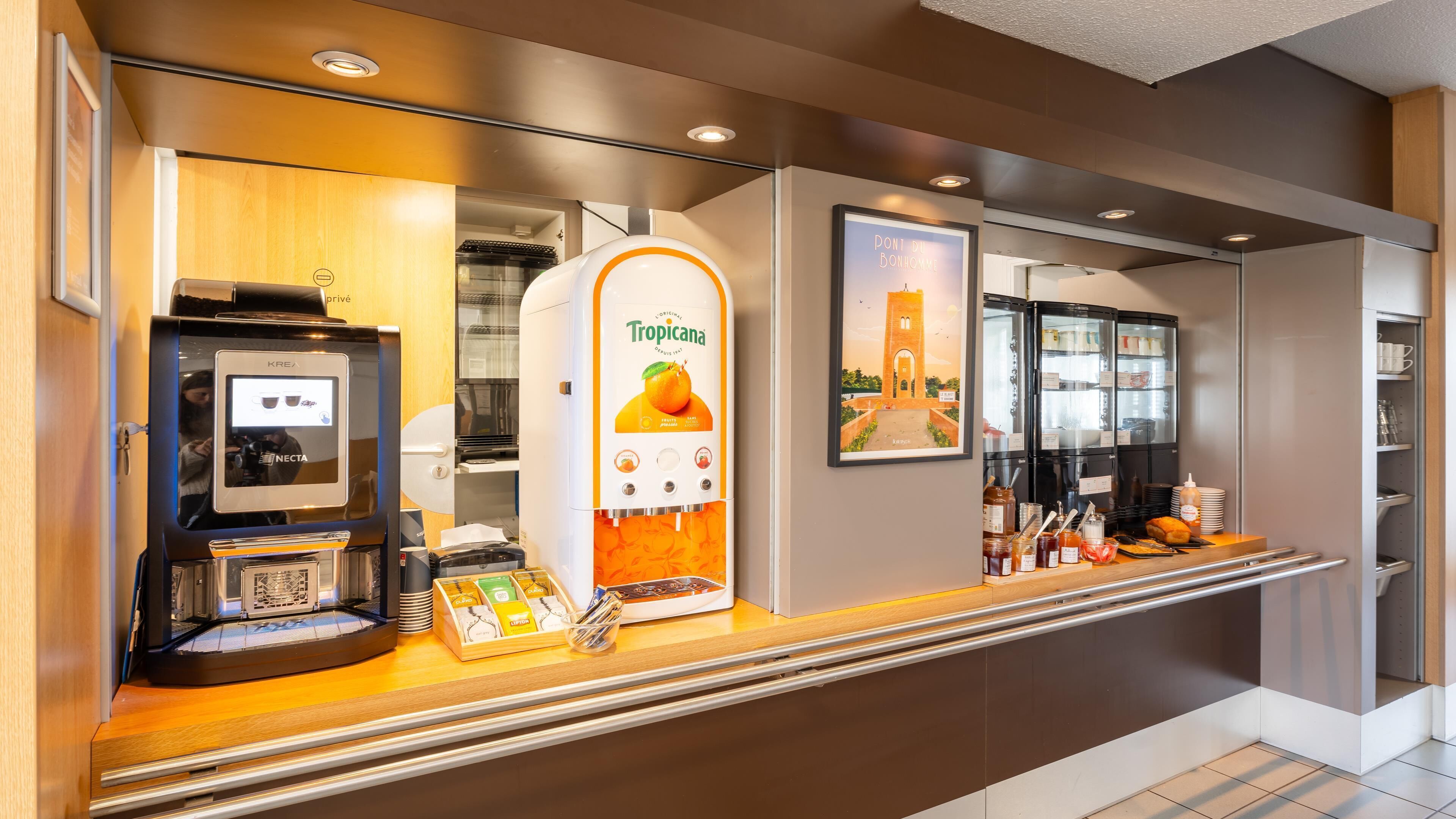 Un quiosco de autoservicio con pantalla táctil, dispensador de jugo Tropicana y máquina de café.