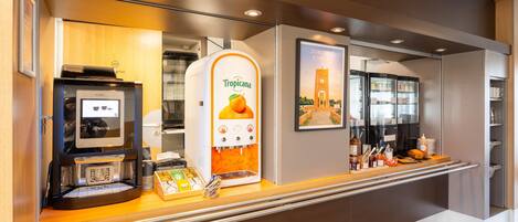 A self-service kiosk with a touchscreen, a Tropicana juice dispenser, and a coffee machine.