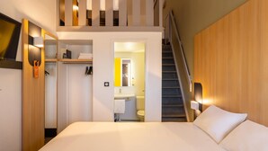 A hotel room with a bed, a bathroom, and a staircase. - Kyriad ECO - Lorient Lanester (Lanester)