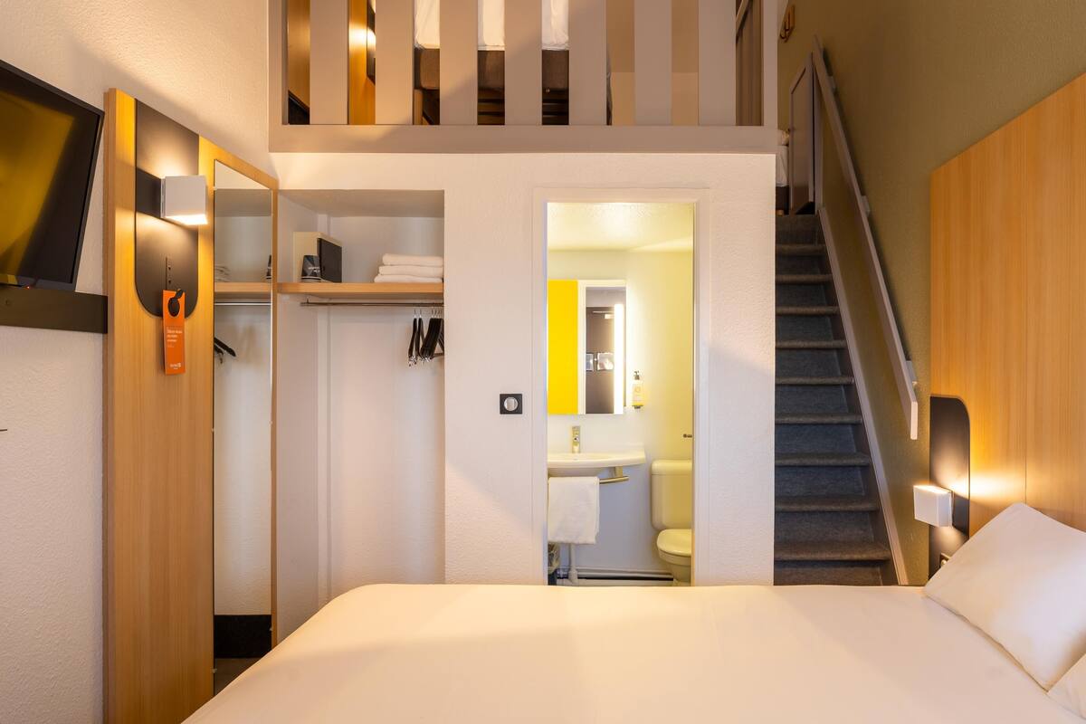 A hotel room with a bed, a bathroom, and a staircase.