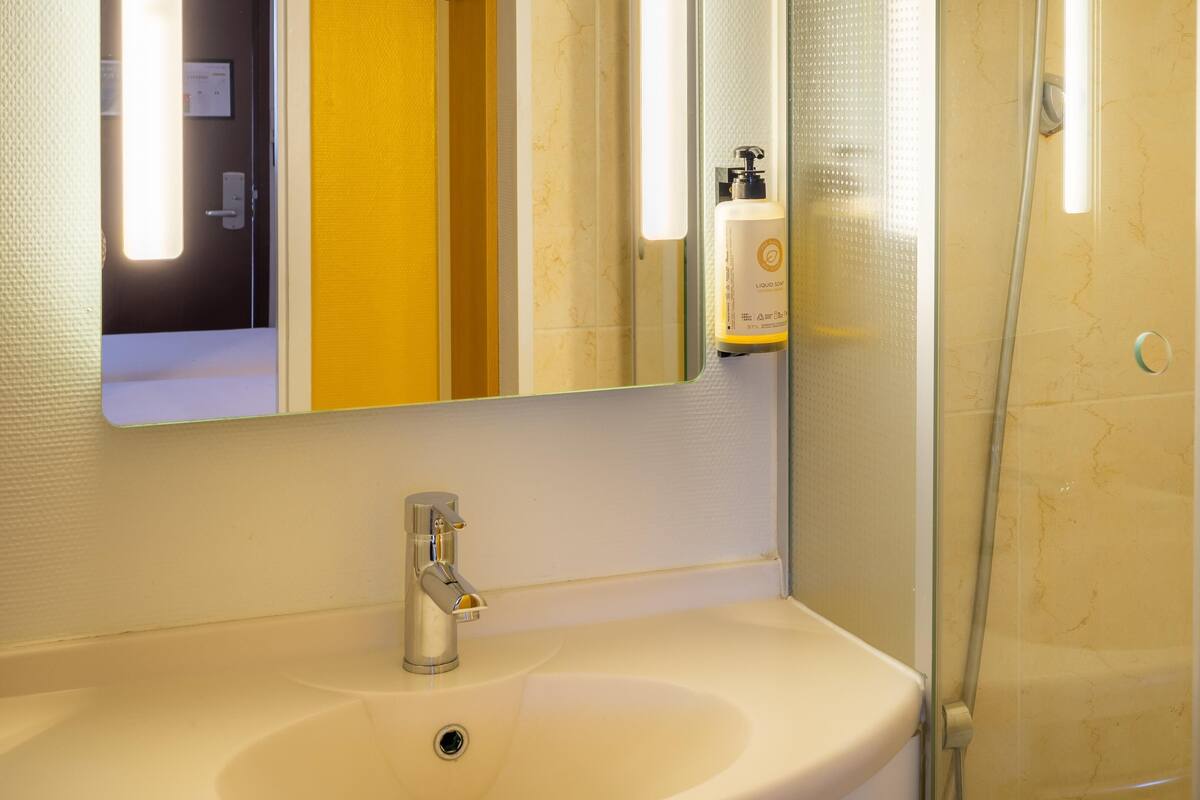 A bathroom with a sink, mirror, and shower.