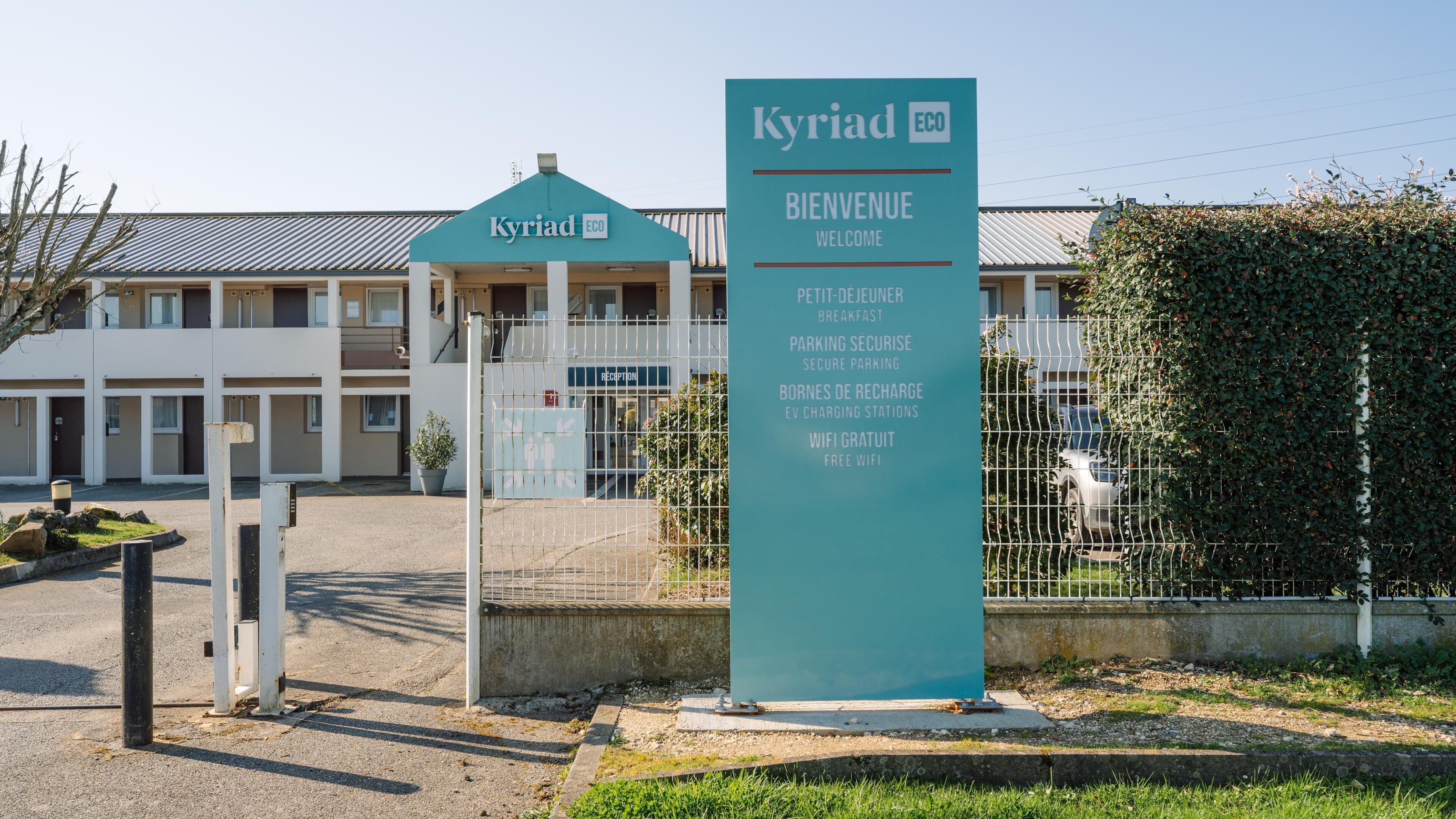 Un cartel con el texto 'Kyriad ECO' y 'BIENVENUE WELCOME', indicando una entrada acogedora a un establecimiento.