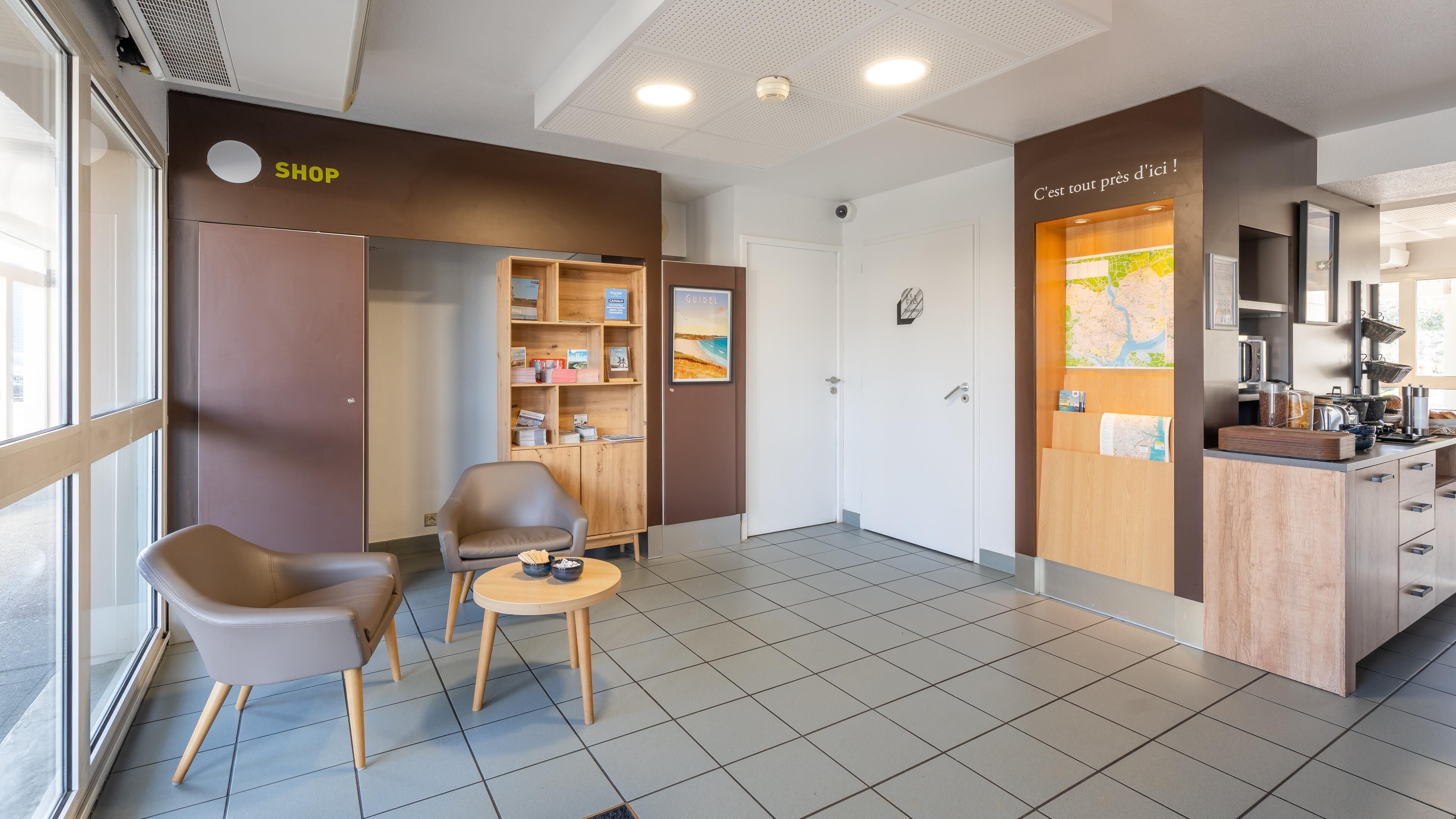 Un moderno vestíbulo de hotel con una tienda, zona de estar y kitchenette.