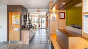 A hotel reception area with a wooden counter, a map, and a fire extinguisher. - Kyriad ECO - Lorient Lanester (Lanester)