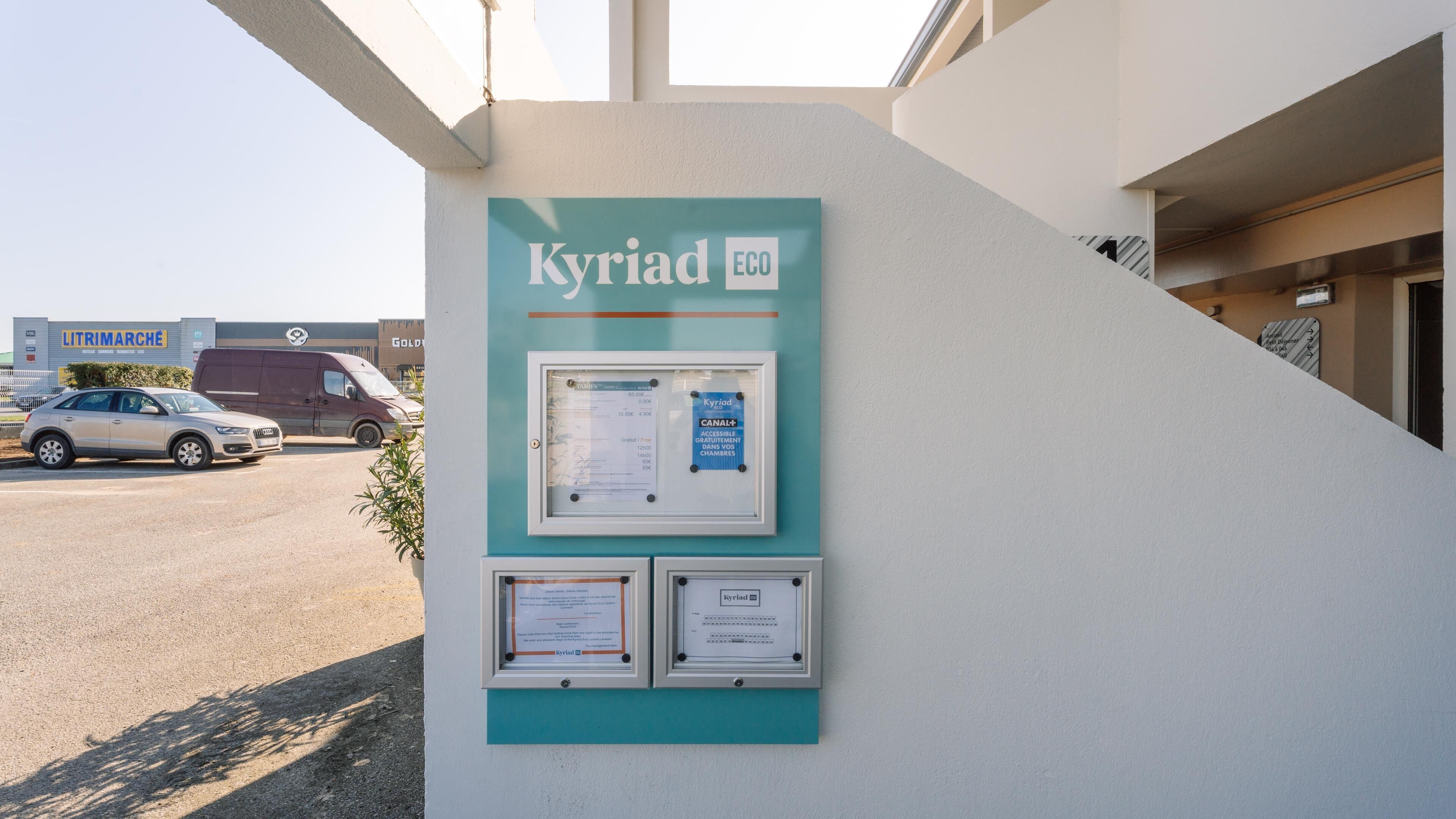 Un edificio con un cartel que dice 'Kyriad ECO' y un marco con documentos.
