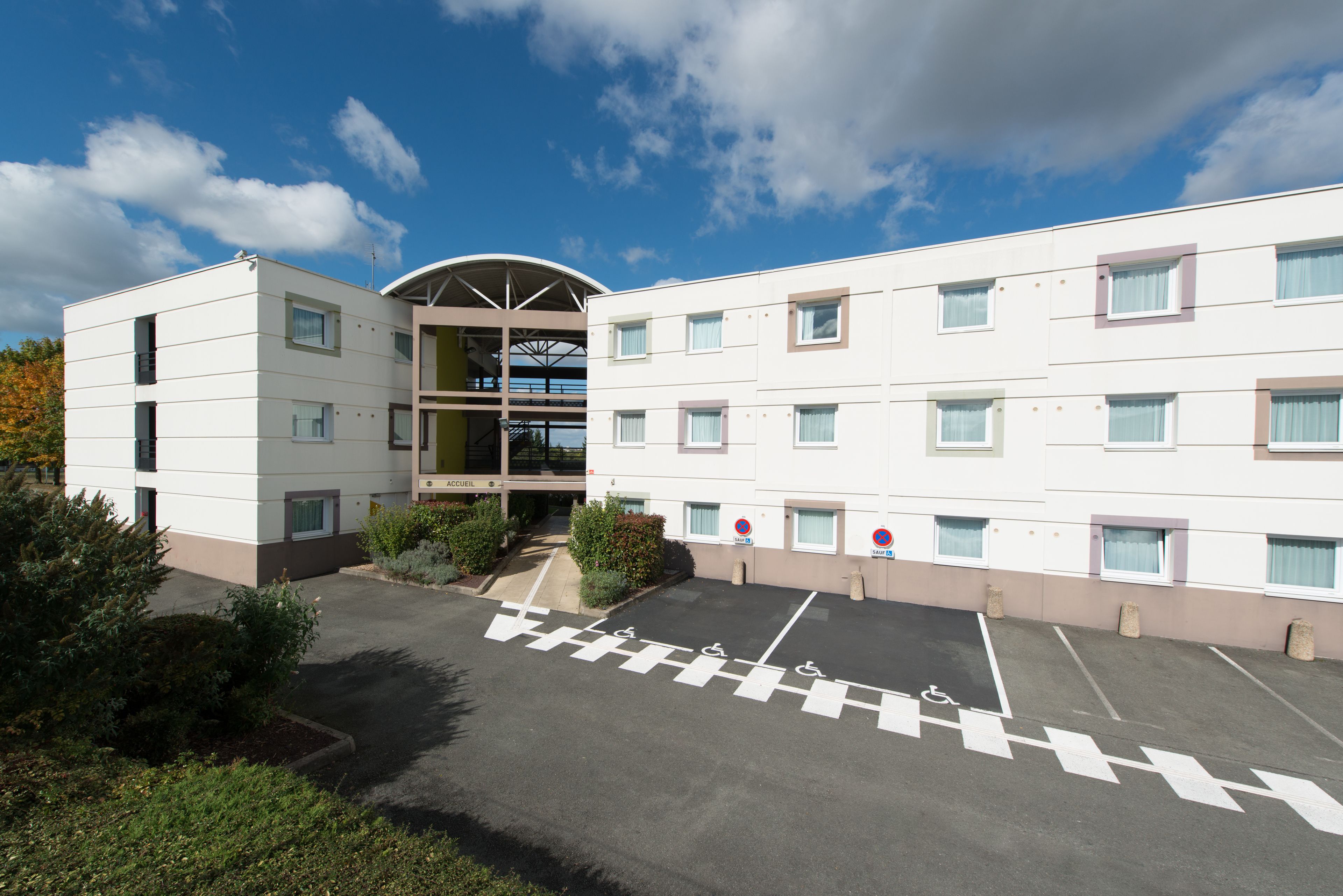Un hôtel moderne doté d’un atrium central, de plusieurs étages et d’un parking avec des places réservées.