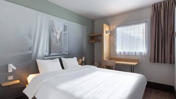 A hotel room with a large bed, a desk, a chair, a wardrobe, and a window with curtains.