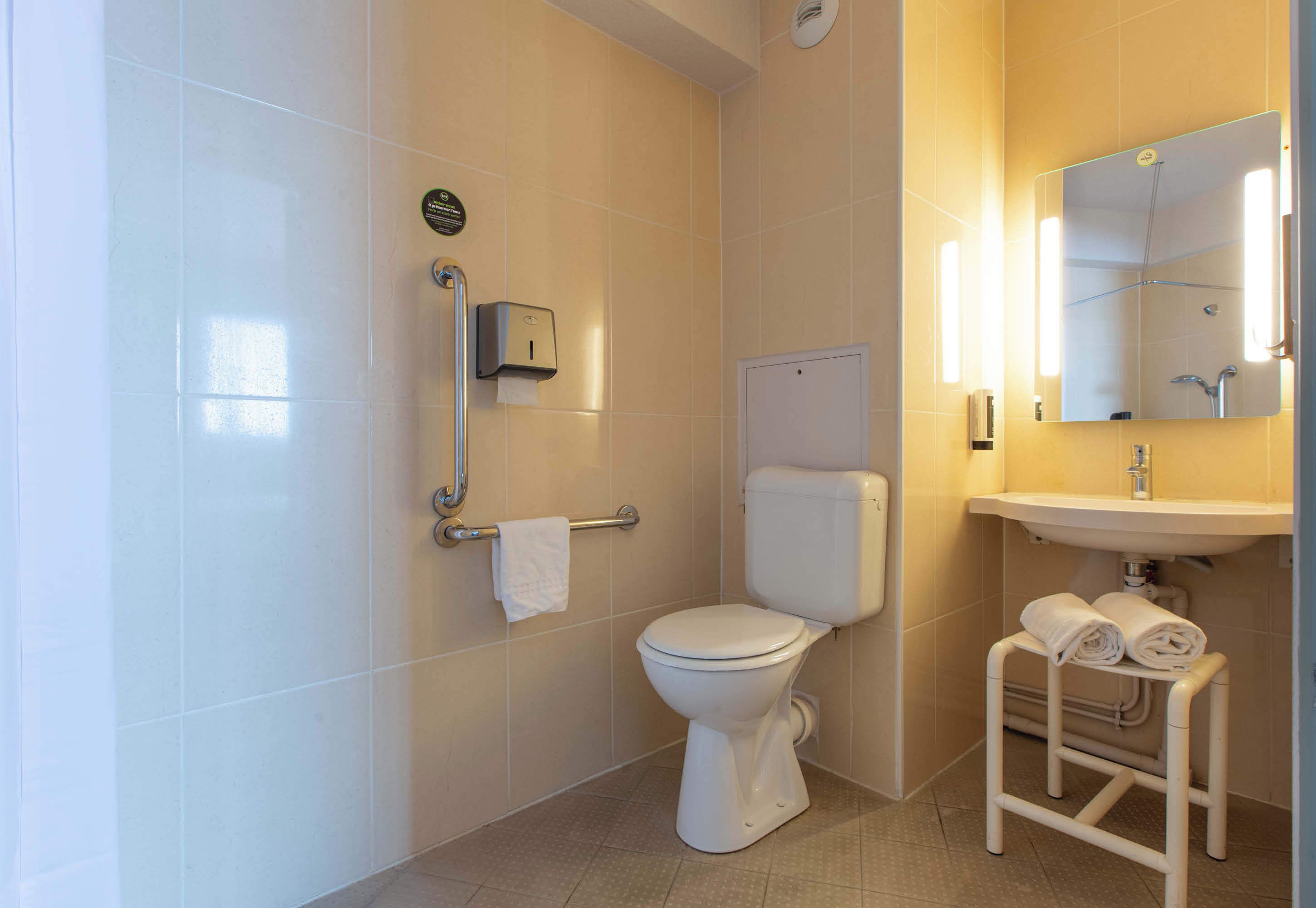 Un bagno moderno con il water, un asciugamani ad aria, un portasciugamani e un lavandino con specchio.