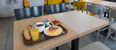 Un desayuno con una bandeja que contiene tostadas, huevos revueltos y una taza de café.