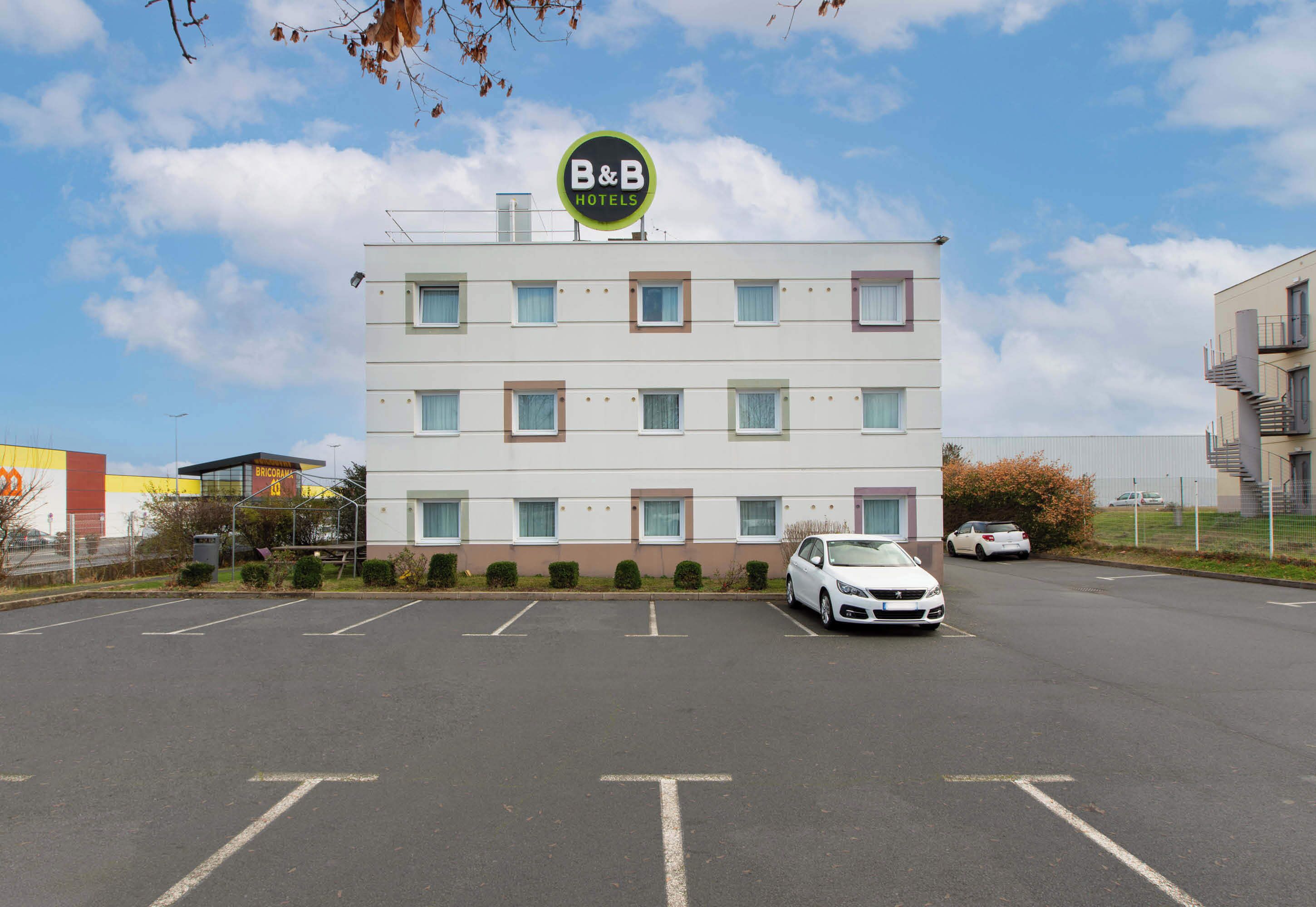 A B&B hotel with a sign, a parking lot, and a white car parked in front.