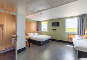 Ein Hotelzimmer mit Bett, Schreibtisch, Dusche, Fernseher und einem Fenster mit Blick.