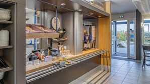 Una barra de petitdejuni moderna amb una màquina de cafè, cistos de pa i diferents articles per esmorzar.