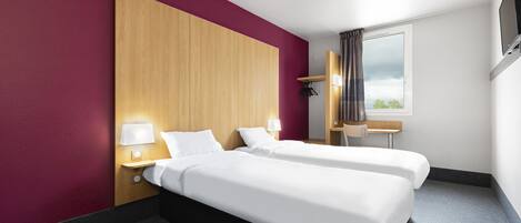 Habitación de hotel con dos camas, cabecero de madera, escritorio y ventana con cortinas.
