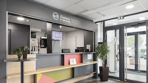 Una recepción con una pantalla digital, un reloj y un letrero que dice "Bienvenue chez B&B".