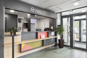 Una recepción con una pantalla digital, un reloj y un letrero que dice "Bienvenue chez B&B".