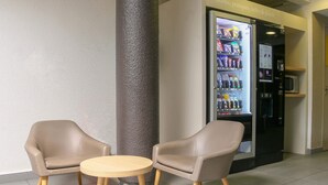 Un espace détente avec deux chaises et une table ronde, un distributeur automatique et un four à micro-ondes.